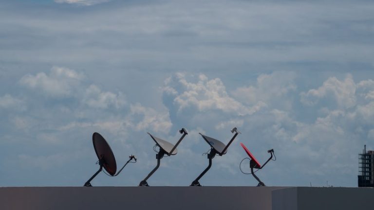 Four satellite dishes on a rooftop against a cloudy sky in Cancún, Mexico.