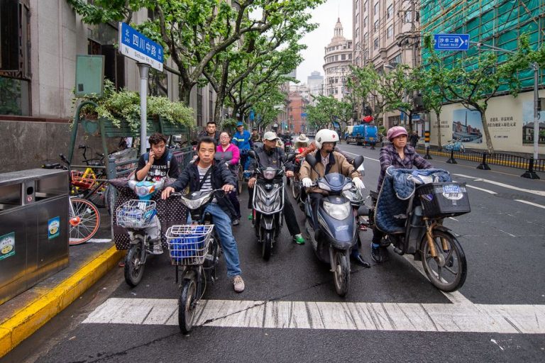 Daily urban commute on Sichuan Road, Shanghai, showcasing bicycles and scooters in a bustling city environment.