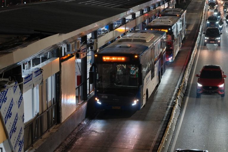 Nighttime view of buses and traffic on a busy street in Jakarta, Indonesia.