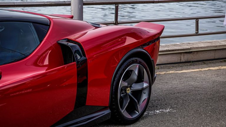 Detailed side view of a sleek red sports car parked by the waterfront.