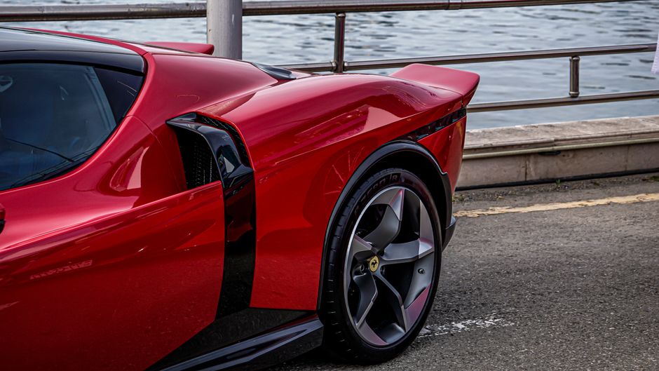 Detailed side view of a sleek red sports car parked by the waterfront.