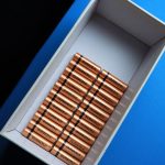 Top view of neatly arranged batteries in a box on a contrasting blue surface.
