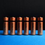 A lined up set of AA batteries with black and blue background.