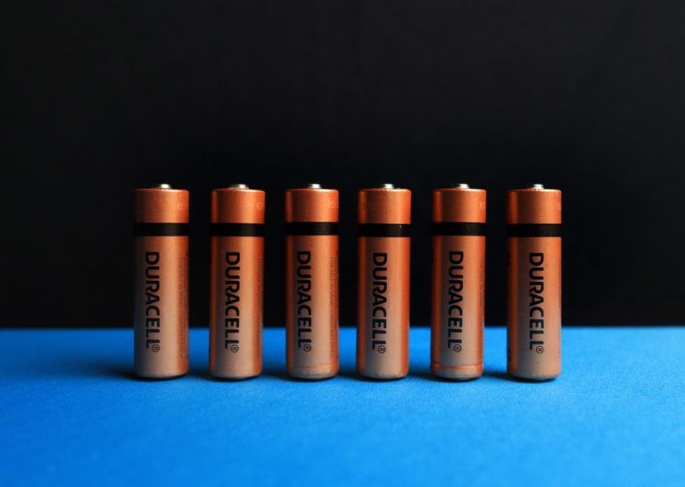A lined up set of AA batteries with black and blue background.