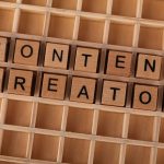 Wooden block letters spelling 'Content Creator' on a grid background. Ideal for digital marketing themes.