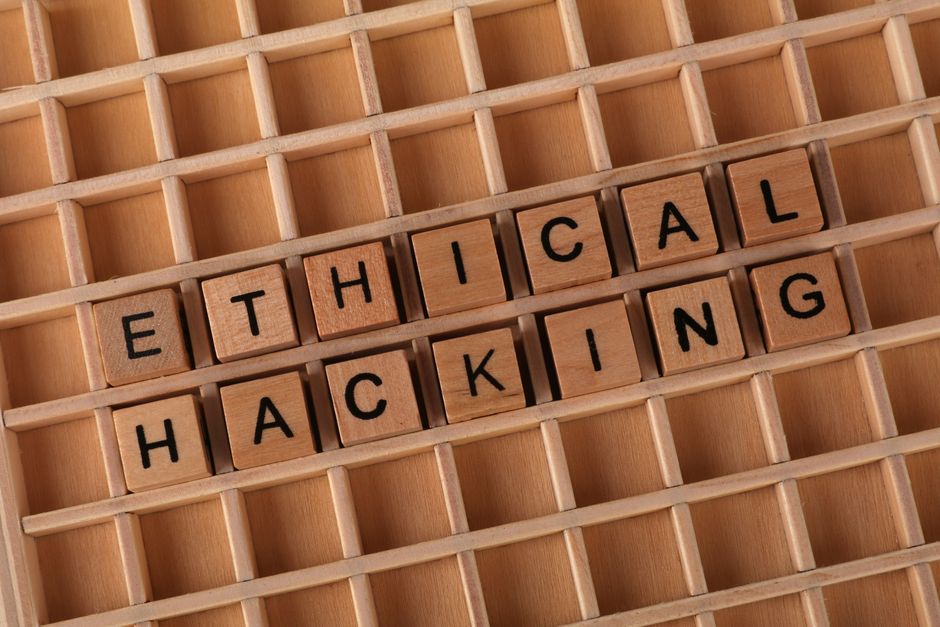 Wooden letter blocks spelling 'Ethical Hacking' on a grid background, symbolizing cybersecurity.