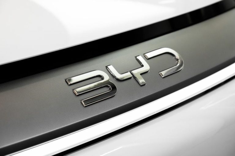 Detailed close-up of the chrome BYD logo on a car, showcasing sleek automotive branding.