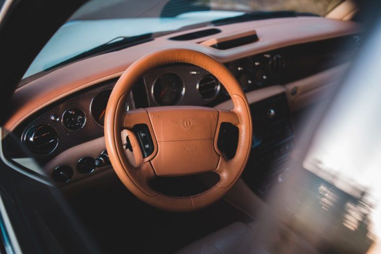 Close-up of a luxurious car interior featuring a leather steering wheel and elegant dashboard.
