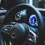 Detailed view of a Mercedes-Benz steering wheel and dashboard, showcasing luxury car interior features.