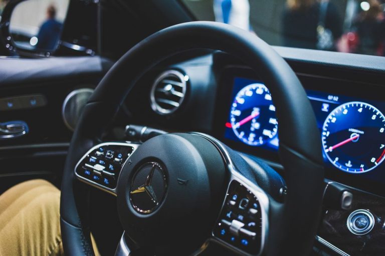 Detailed view of a Mercedes-Benz steering wheel and dashboard, showcasing luxury car interior features.