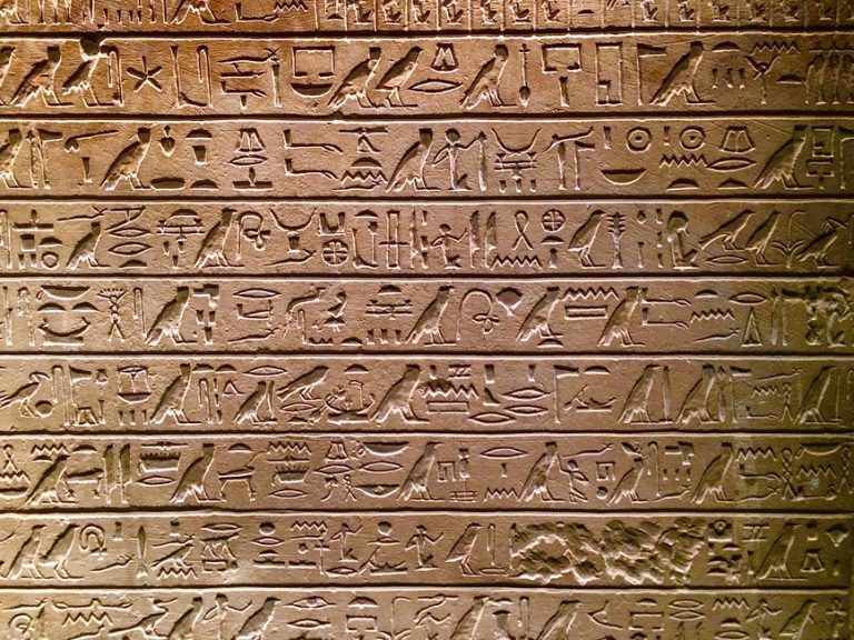Close-up of intricate ancient Egyptian hieroglyphs etched on a stone wall in Berlin.