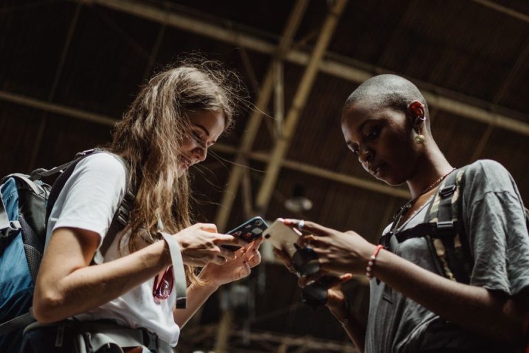 Two women are engrossed in their phones, capturing the essence of modern travel and connectivity.