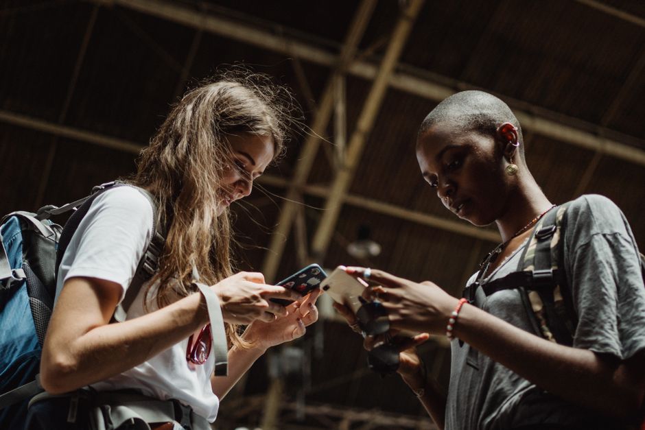 Two women are engrossed in their phones, capturing the essence of modern travel and connectivity.