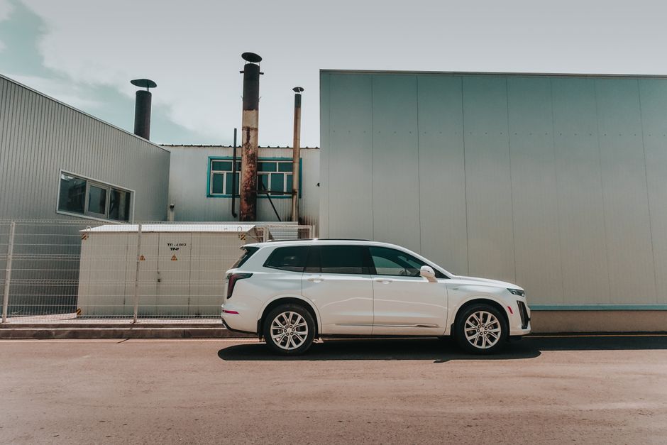 A sleek white SUV parked beside an industrial building in Almaty, Kazakhstan.