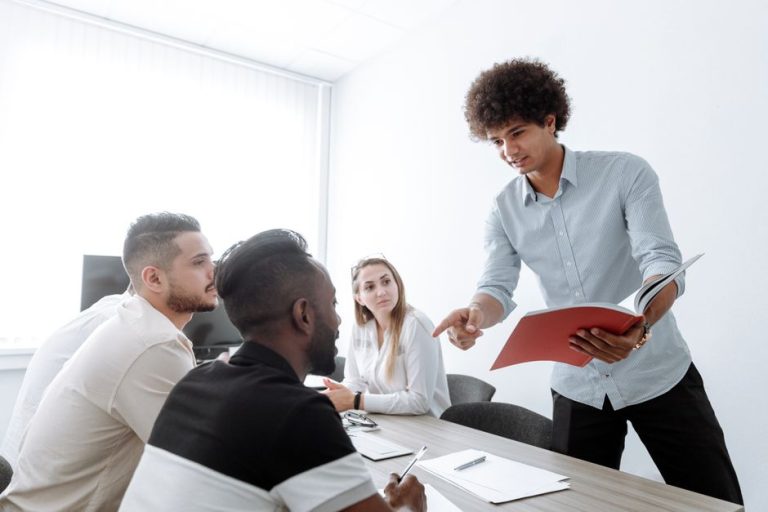 A group of young professionals engaged in a collaborative office meeting, discussing project details.