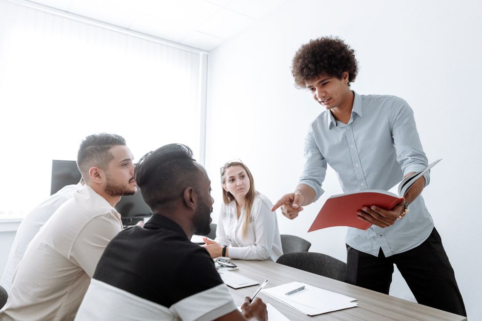 A group of young professionals engaged in a collaborative office meeting, discussing project details.