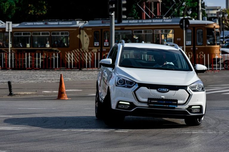 Modern automobile driving on street with tram and traffic cones on sunny day