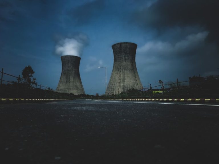 Moody view of industrial cooling towers with smoke against a twilight sky, emphasizing industry impact.