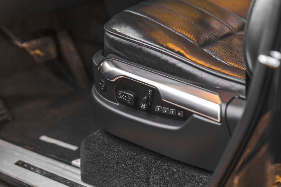 Close-up of a luxury car seat with electric adjustment controls in an SUV interior.