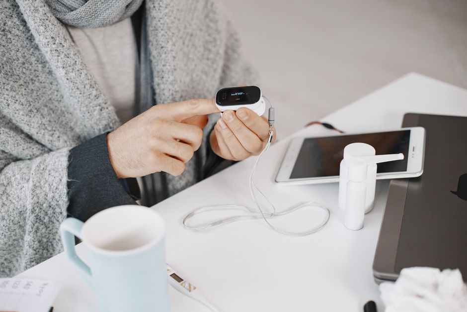 Man in cozy setting reviews a medical device alongside a tablet, focusing on healthcare.