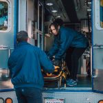 Two paramedics load a stretcher into an ambulance, ready for emergency medical service.