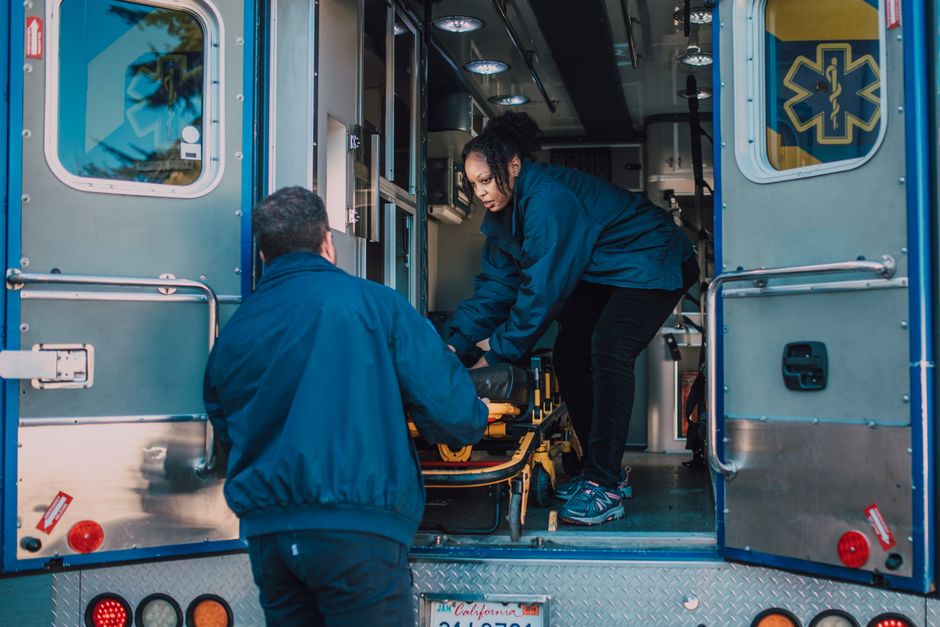 Two paramedics load a stretcher into an ambulance, ready for emergency medical service.