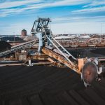Coal loading bucket using for moving coal on conveyor belts in industrial factory under cloudy blue sky in daytime