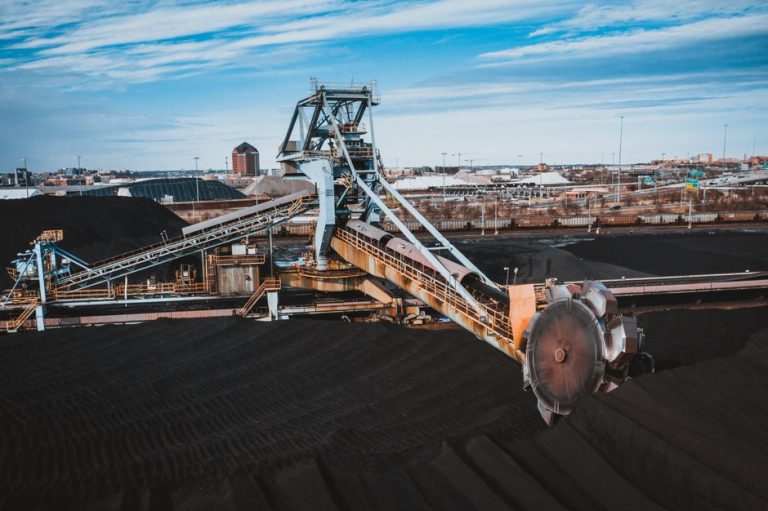 Coal loading bucket using for moving coal on conveyor belts in industrial factory under cloudy blue sky in daytime