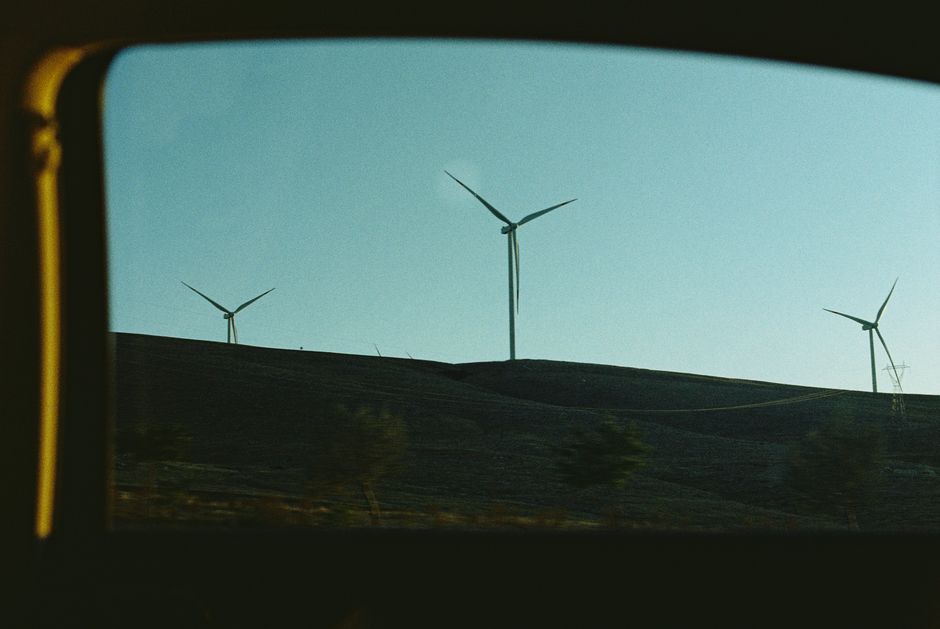 Wind turbines on a hill silhouetted against a clear sky at sunset, symbolizing renewable energy.