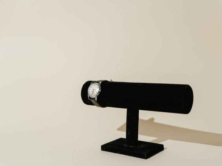 A minimalist shot of a classic wristwatch with leather strap on a black stand.