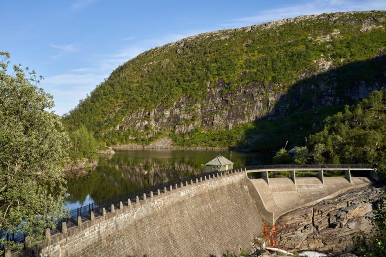 A picturesque view of a water dam nestled in a mountainous landscape reflecting calm waters.
