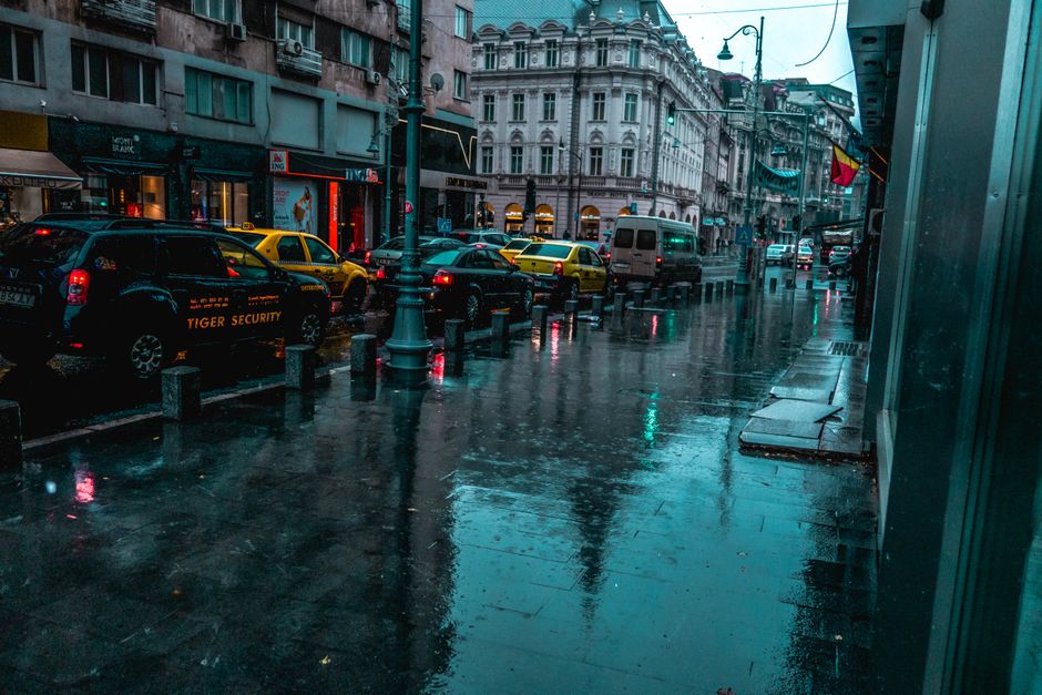A wet city street with traffic and classic architecture, reflecting calm ambiance on a rainy day.