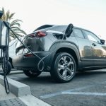 Modern electric vehicle charging at an outdoor station in daylight.