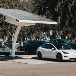 Electric car parked at a solar charging station outdoors, highlighting renewable energy and innovation.