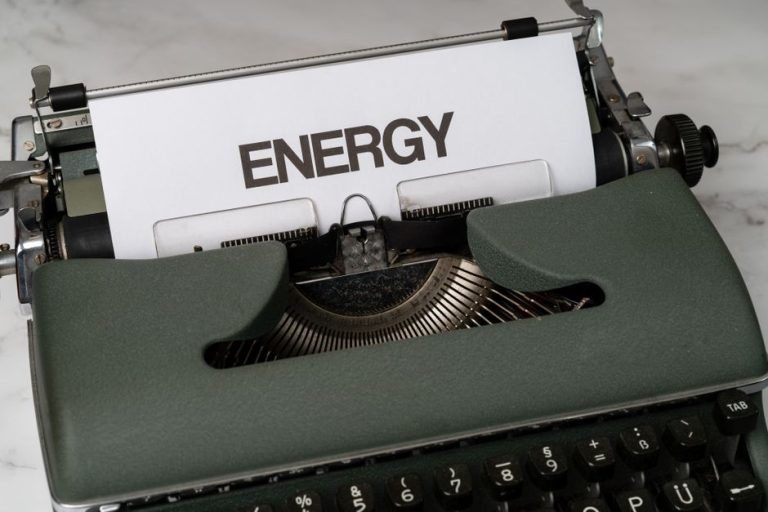 Close-up of a green vintage typewriter with paper showing the word 'Energy' in bold.