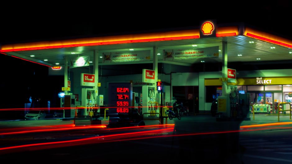 Illuminated Shell gas station with long exposure light trails at night.