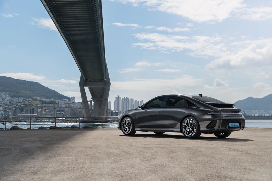 Sleek electric Hyundai car parked under a modern bridge in Busan, South Korea.
