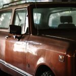 Close-up of a vintage SUV showcasing its retro design in a dimly lit indoor setting.