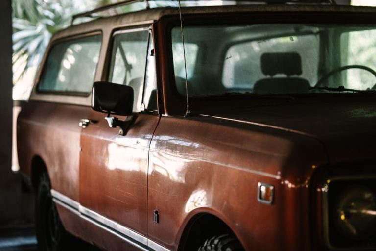Close-up of a vintage SUV showcasing its retro design in a dimly lit indoor setting.