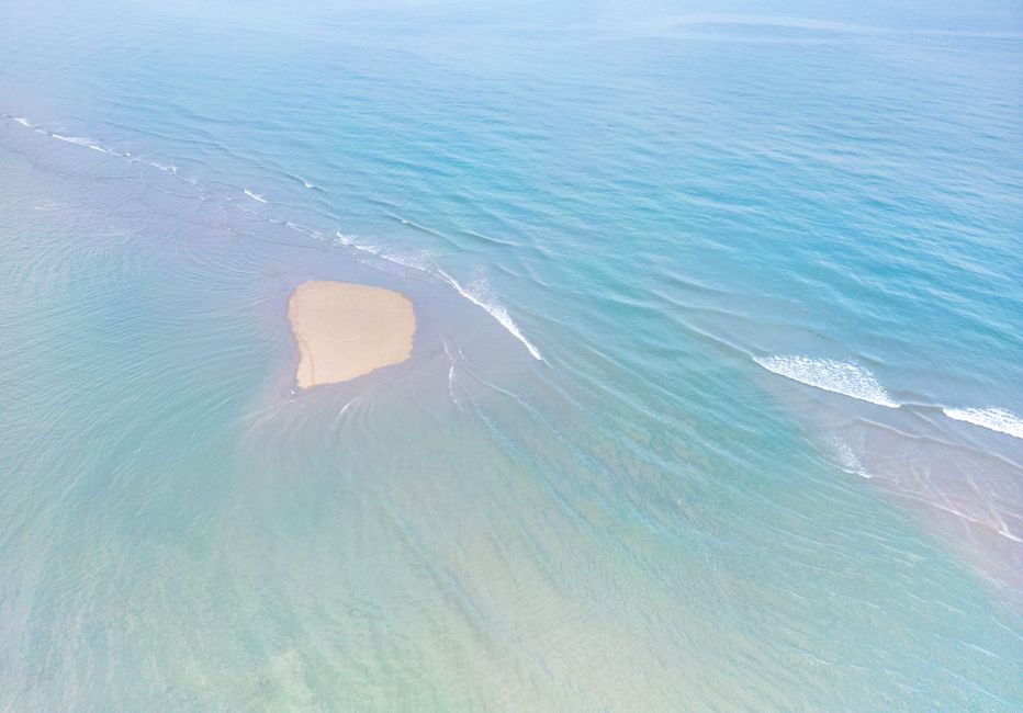 Drone captures a sandy shoal surrounded by clear turquoise waters, highlighting serenity.