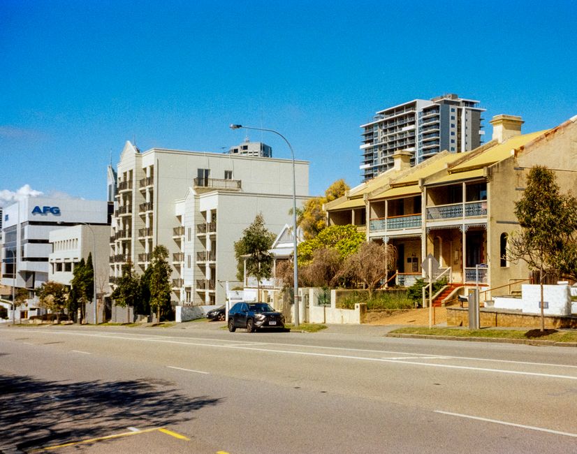 Street view showcasing a blend of modern and vintage architecture, capturing urban life in daylight.