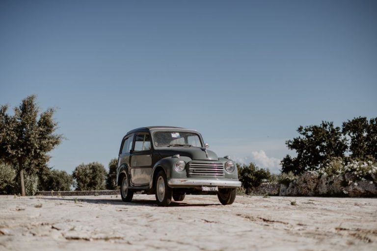 Classic Fiat 500 Topolino parked outdoors in Ostuni, Apulia, Italy under a clear, sunlit sky.