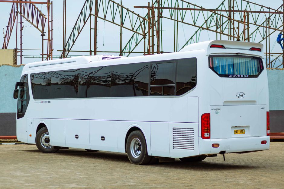 White bus parked in an open lot under a clear sky, showcasing modern design.