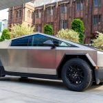 A modern electric truck parked in front of historic Manchester architecture.