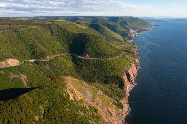 Explore the breathtaking cliffs and coastline of Cape Breton Highlands, showcasing lush green hills and rugged ocean views.