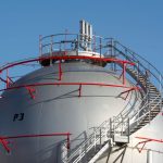 Close-up view of a large industrial gas storage sphere with a surrounding metal staircase.