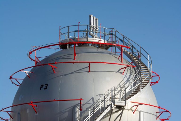 Close-up view of a large industrial gas storage sphere with a surrounding metal staircase.
