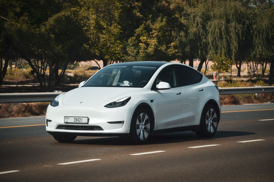 A sleek white electric car cruising on a sunny highway in Abu Dhabi, UAE.