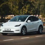 A sleek white electric car cruising on a sunny highway in Abu Dhabi, UAE.