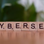 Wooden tiles spell 'CYBERSEC' against a soft-focused green background.